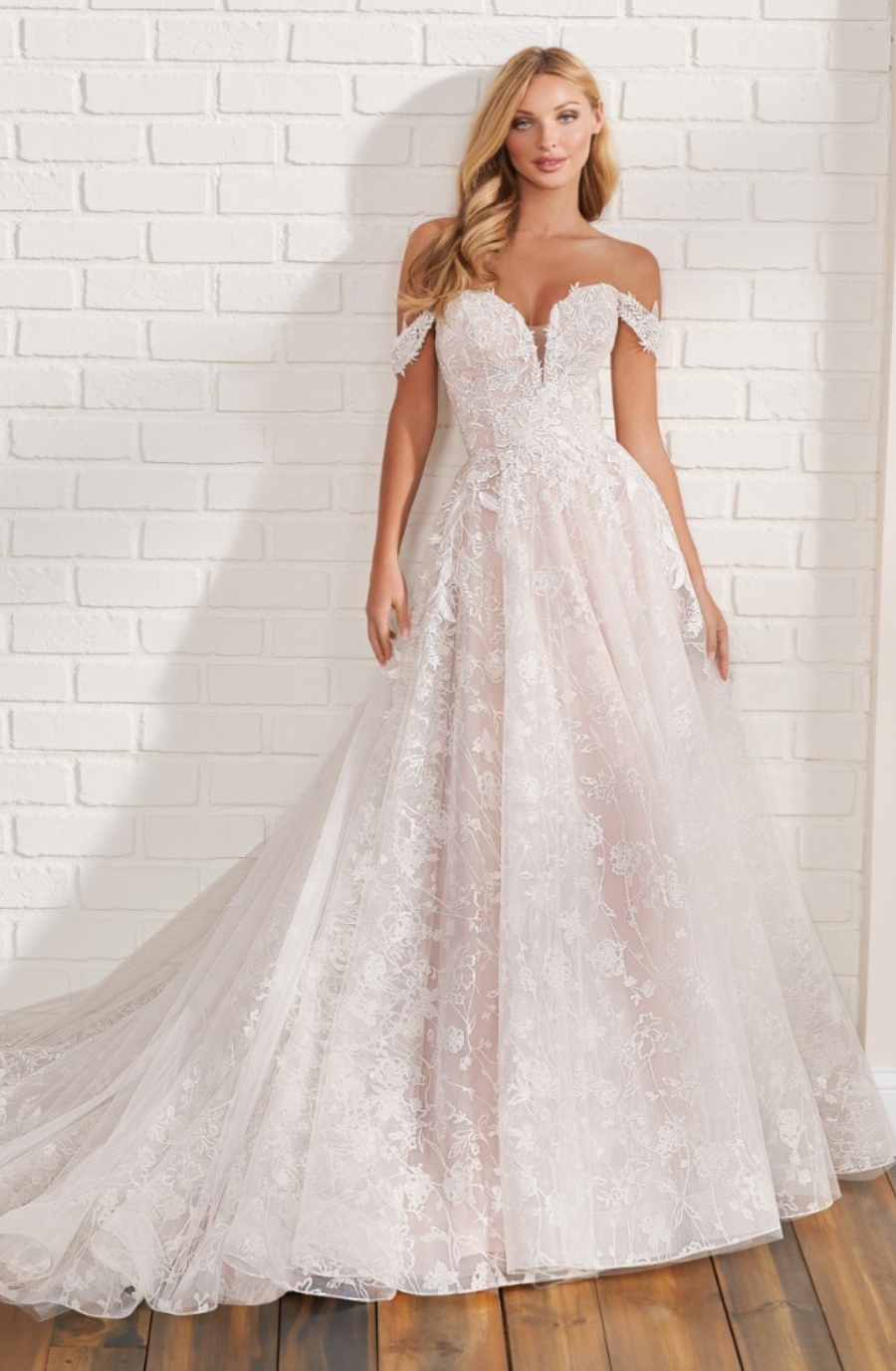 model is wearing a lace off the shoulder long sleeve fit and flare wedding dress