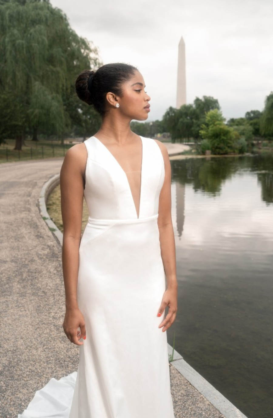 model is wearing a sleeveless plunging neckline satin bridal gown