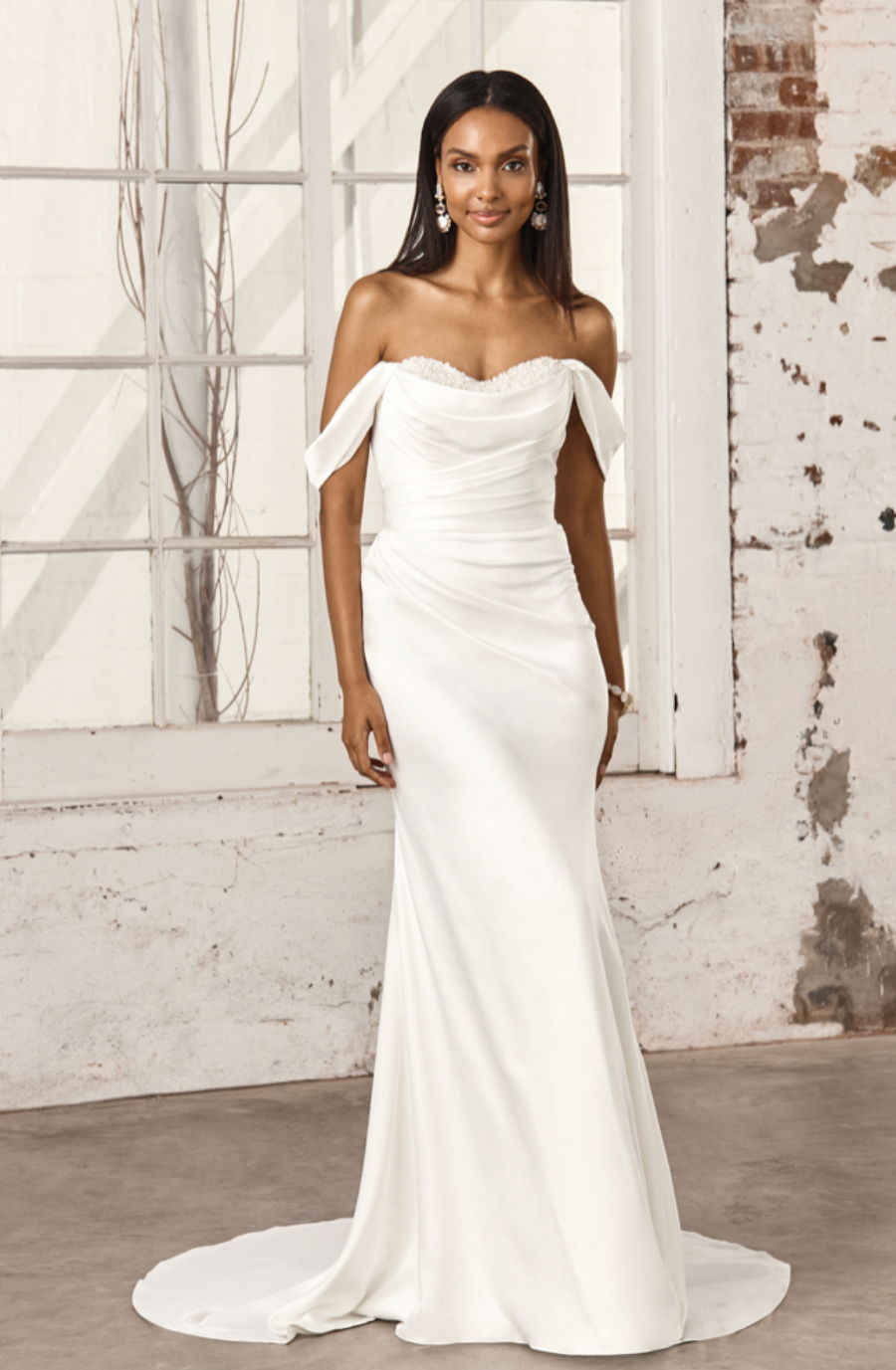 model is wearing an off the shoulder satin wedding dress